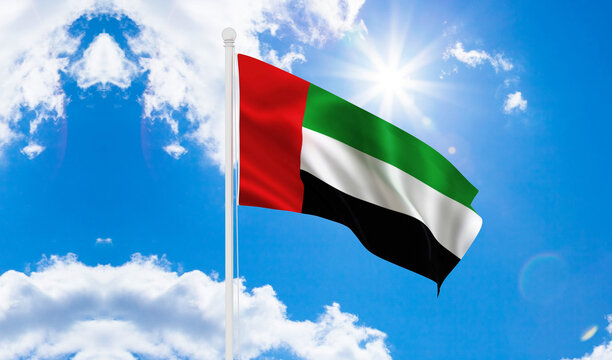 Flag of United Arab Emirates flag waving in the wind, sky and sun background. United Arab Emirates Flag.