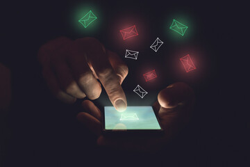 Smartphone in the hands of a person and also envelopes on a dark background. A finger touches the screen. Red and green envelopes. Spam and useful mail concept. - obrazy, fototapety, plakaty