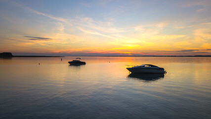 Fototapeta na wymiar Docked sailboats. Beautiful sunset over the lake. Clouds on orange sky during summer sundown. 