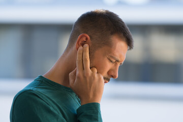 Man with tinnitus. Man touching his ear because of strong earache or ear pain. Otitis - obrazy, fototapety, plakaty