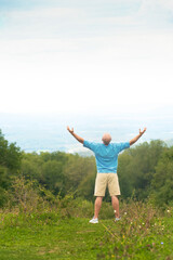 A man of athletic build, a traveler spread his arms to the side against the backdrop of a mountain. High quality photo