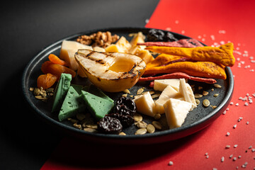 food on a plate with cheese, nuts, pear, apricot, prune and etc