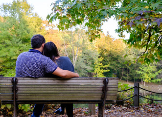 Fototapeta premium Couple sitting on bench and hugging each other in the forest, retirement concept idea with copy space