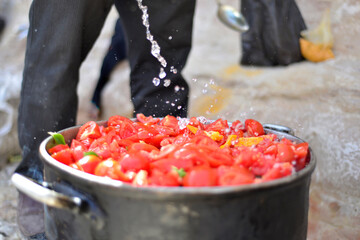 man cooking tomato soup on camp fire. wild nature resting. cutting tomatoes. Chopped juicy canned tomatoes in big bowl, tomato soup