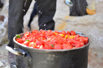 man cooking tomato soup on camp fire. wild nature resting. cutting tomatoes. Chopped juicy canned tomatoes in big bowl, tomato soup