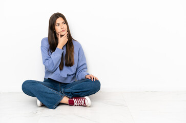 Young woman sitting on the floor having doubts and with confuse face expression
