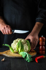 Cook is cutting cauliflower in a restaurant kitchen. The idea of a delicious diet for breakfast or dinner