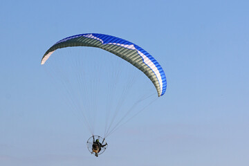 Paramotor pilot flying in a blue sky