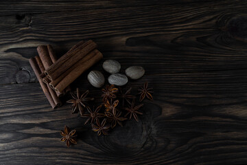 Natural cinnamon stick seasoning with anise stars and nutmeg on a brown wooden background, top view