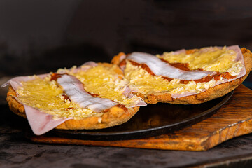 Close-up shot of two halves of a bun with cheese and bacon on a round plate for making a burger
