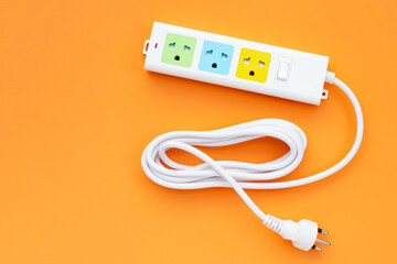 Electrical power strip and plug on orange background. Top view