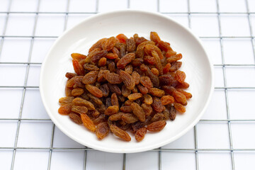 Dried grape raisins in white plate on white background