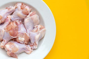 Fototapeta na wymiar Fresh raw chicken wings (wingstick) in white plate on yellow background.