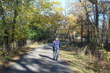 Middle-aged man walking on the North Branch trail in autumn at Blue Star Memorial Woods in...