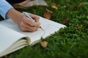 Side view of woman hands writing in notebook,  outdoor worker, remote work.