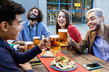 Group of hipster friends enjoying drink at bar terrace - Young happy students having fun toasting beer at campus university - Teamwork, friendship, unity and millennial people concept