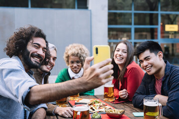 Group happy friends taking selfie photo in outdoors restaurant bar to share celebration on social media