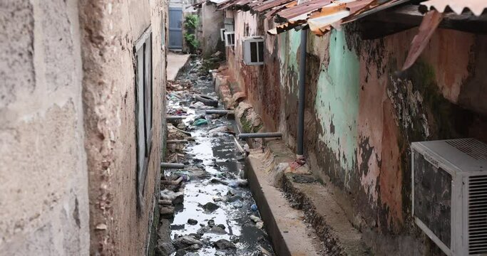 Alley between homes raw sewer ditch Accra Ghana. Historical busy congested market residential area Accra, Ghana. Pollution and garbage. Homes low income poverty of Africa. Disease illness.