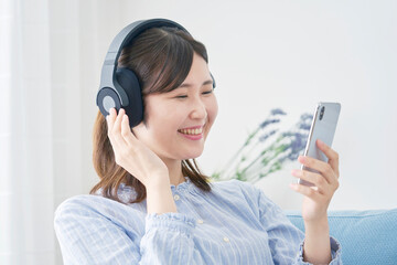 女性　リビング　スマホ　ヘッドホン