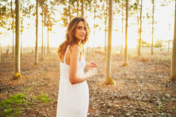 Charming ethnic woman standing in sunny forest