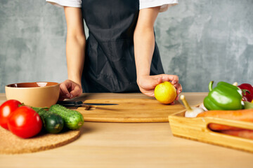 Obraz na płótnie Canvas Woman in black apron on the kitchen cutting vegetables