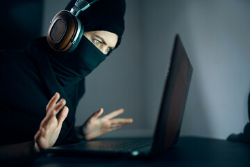 woman in mask in front of laptop headphone hacking