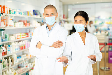 Portrait of two pharmacists in medical masks and white coats in a pharmacy