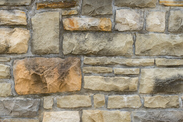 A wall made from irregular stone blocks. Assortment of different shape stones as background