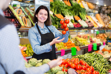 friendly female seller assisting customer to buy fresh fruit and vegetables in grocery shop