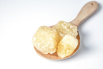 Rock sugar in wooden spoon on white background.