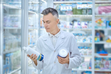 Satisfied man in white coat holding medical products