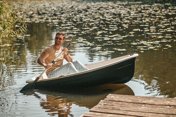 Fototapeta na wymiar Smiling man with paddle in boat