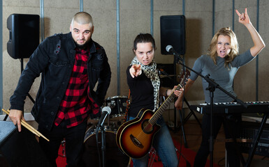 Positive guitarist, drummer and keyboardist of rock band in sound studio