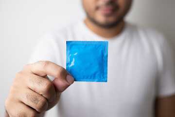 The young man showing the condom into camera. Campaign for safe sex and contraception. Close up...