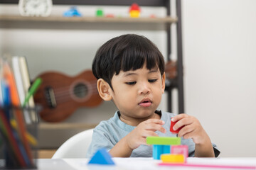 Asian little boy education from home. Developing children's learning before entering kindergarten Practice the skills of playing with wooden toys in living room.