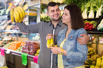 Obraz premium Young smiling couple choosing fruits in grocery shop
