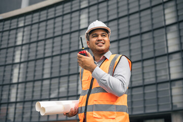 Asian engineer holding radio operate and control the worker employee to build construction. Young ...