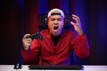Angry asian gamer man playing computer pc. He lose in the game. Missed the chance to become a...