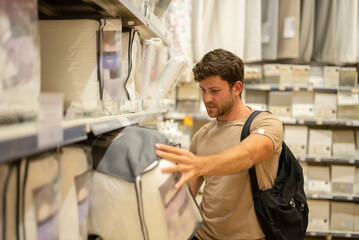 Content guy picking pillows in linen store