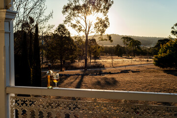 Australian verandah scene with sunset and wine bottle - obrazy, fototapety, plakaty