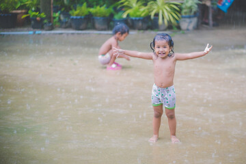 Happy asian little child girl having fun to play with the rain in the evening sunlight 