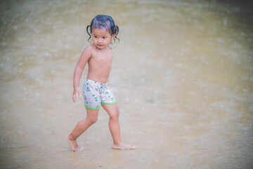 Happy asian little child girl having fun to play with the rain in the evening sunlight 