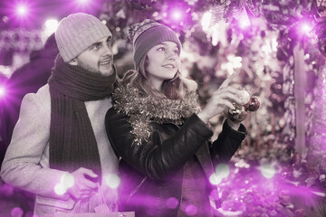 Fototapeta premium Portrait of joyful young couple with Christmas toys at fair outdoor