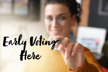 Young woman writing text EARLY VOTING HERE on transparent board