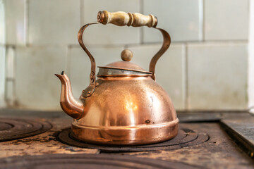 Close-up of a vintage brass teapot on an old wood stove