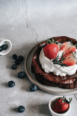 Flourless chocolate cake with whipping cream and strawberry on concrete background. Homemade cake concept.