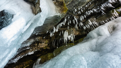 Bizarre stalactite icicles hang from the granite vault of the cave. The walls of the grotto are...