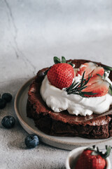 Flourless chocolate cake with whipping cream and strawberry on concrete background. Homemade cake concept.