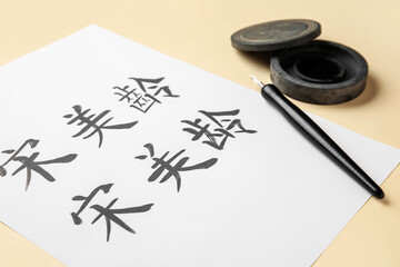 Tools for calligraphy and paper with Asian hieroglyphs on color background