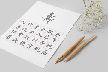 Tools for calligraphy and paper with Asian hieroglyphs on light background